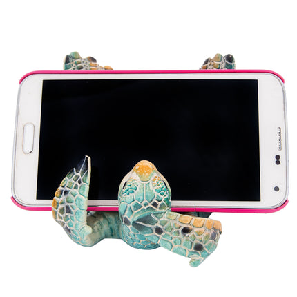 Phone holder shaped like a turtle with a smartphone on a white background