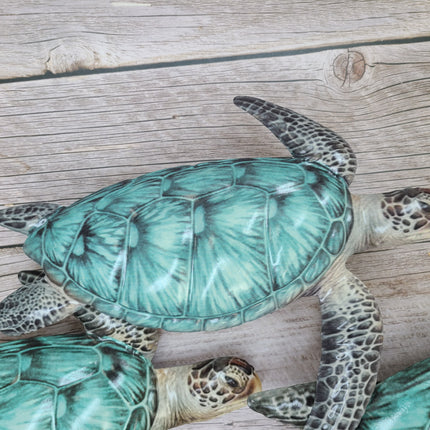 Three aqua blue metal sea turtles swimming in a family group, detailed coastal wall sculpture for beach-themed home decor.