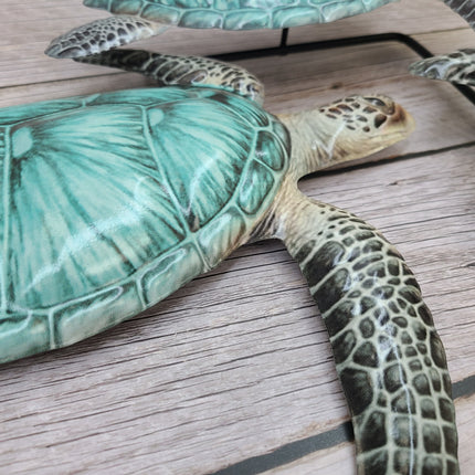 Three aqua blue metal sea turtles swimming in a family group, detailed coastal wall sculpture for beach-themed home decor.