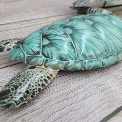 Three aqua blue metal sea turtles swimming in a family group, detailed coastal wall sculpture for beach-themed home decor.